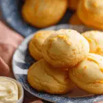 Freshly baked orange cookies in a sunlit kitchen with oranges and baking tools.