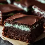 Stack of classic three-layer mint brownies with fresh mint