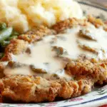 Crispy buttermilk chicken fried steak with country gravy served on a plate.