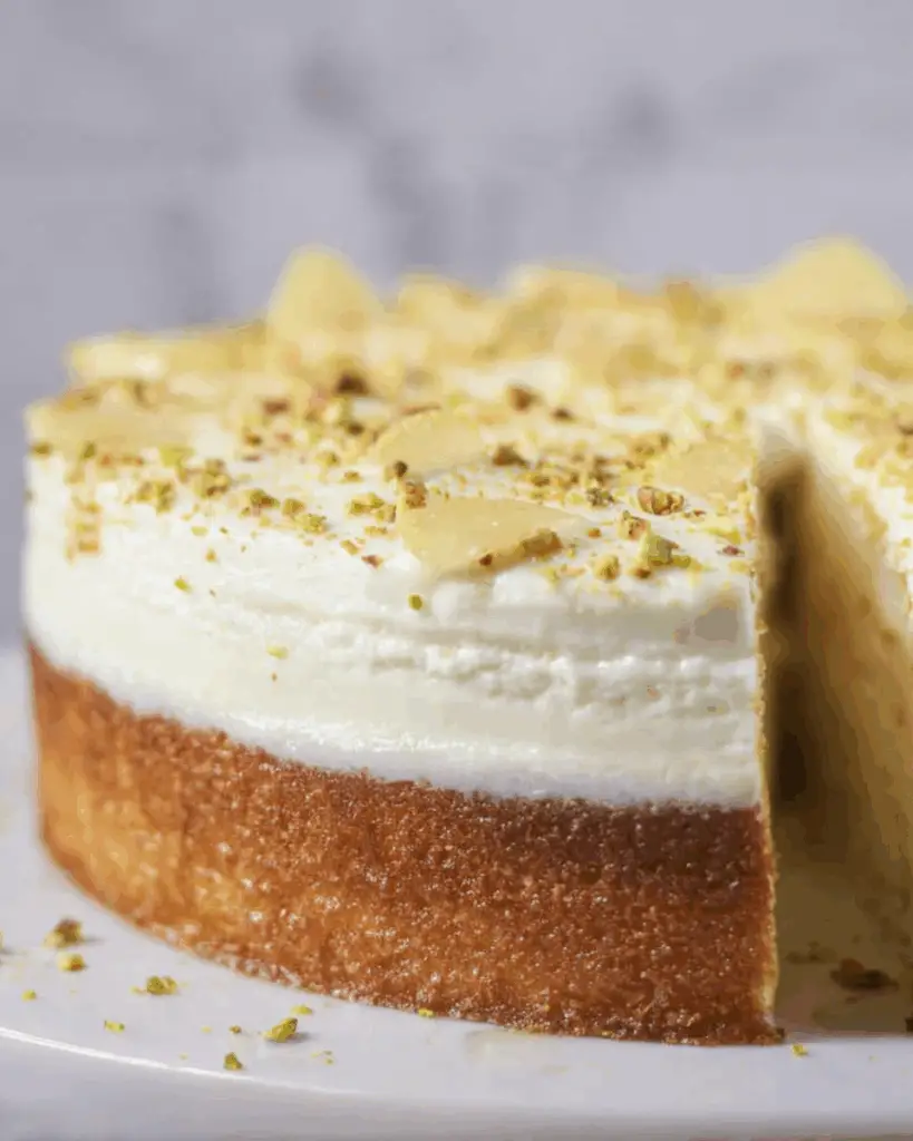 Sliced lemon pistachio ricotta cloud cake served with cream and lemon peel